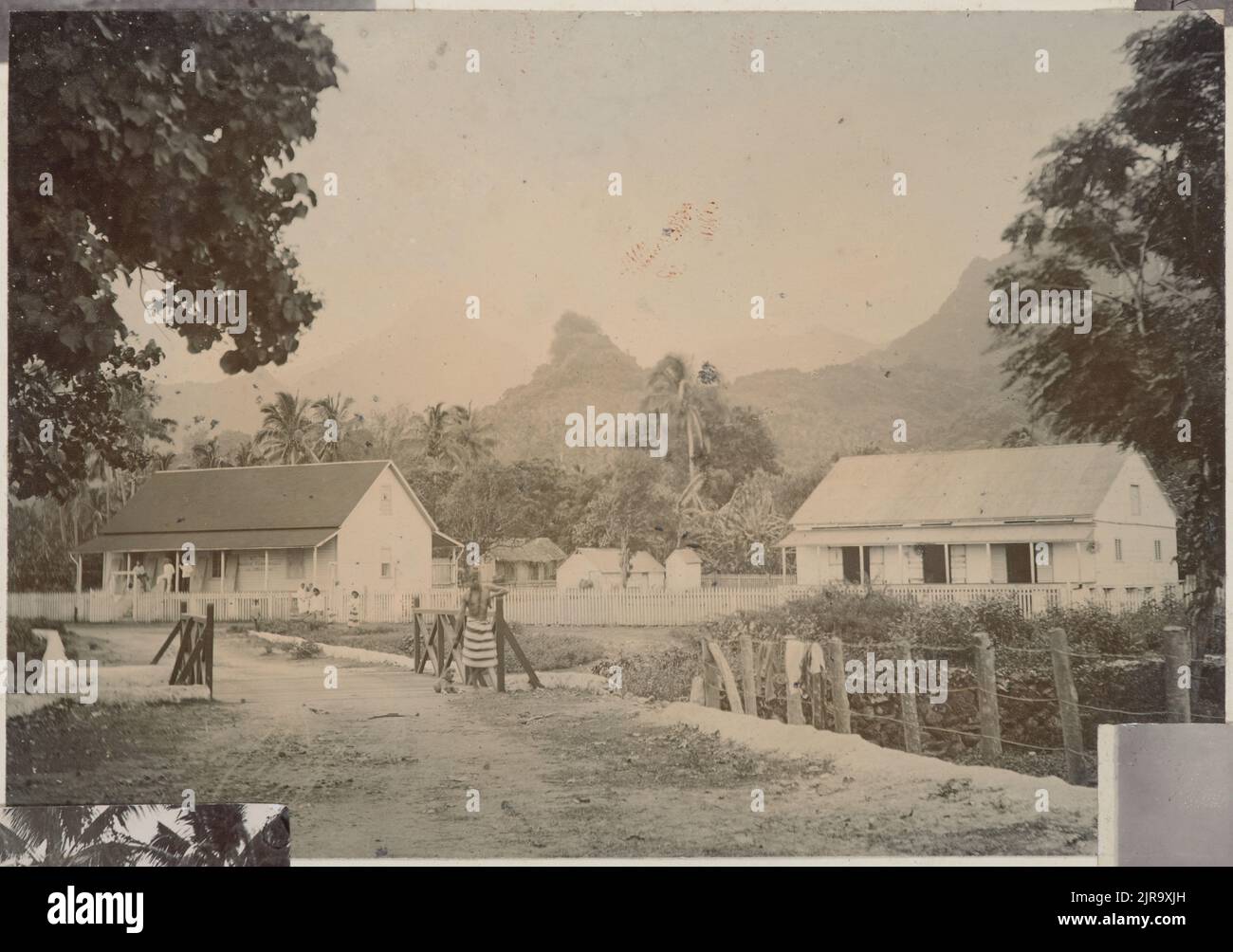 Faites cuire l'homme Islander sur un pont en face de bâtiments en bois. Extrait de l'album: Cook Islands, vers 1896, Rarotonga, fabricant inconnu. Banque D'Images