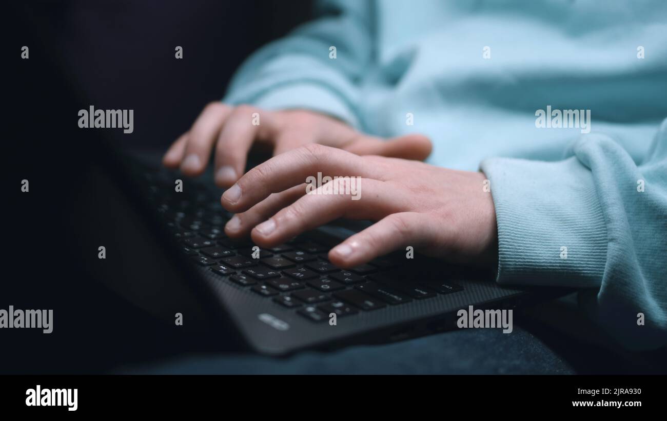 Vue rognée des mains des développeurs Web assis dans un abri de bombe sombre, pendant la guerre en tapant le code sur le clavier et en créant un site Web sur un ordinateur portable Banque D'Images