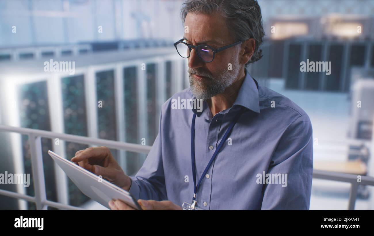 Un spécialiste informatique utilise Digital Pad dans un centre de Cloud Computing ou un centre minier de Big Server Farm, pour surveiller la cybersécurité et l'état des serveurs. Panoramique grand angle autour de la vue. Banque D'Images