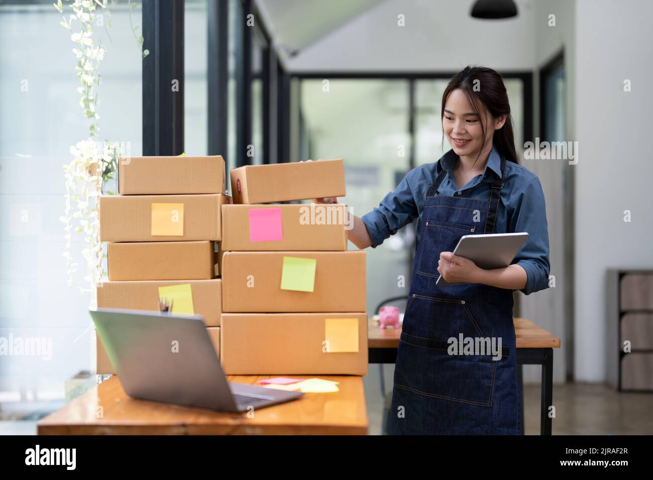 Jeune femme asiatique attrayante propriétaire startup affaires avec boîte à la maison préparer livraison de colis dans la chaîne d'approvisionnement des pme, concept d'approvisionnement. Banque D'Images