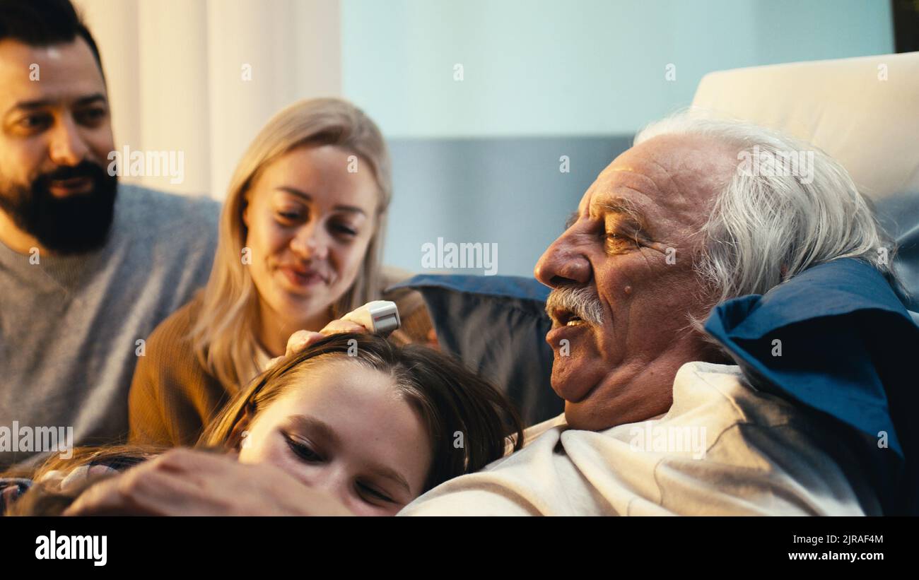 Un homme âgé embrassant des enfants heureux près d'une mère adulte et d'un père rendant visite à un patient dans la salle d'hôpital Banque D'Images