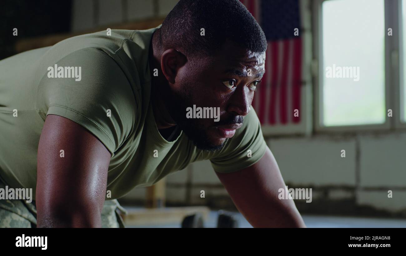 Homme noir qui fait des push-up et prend le repos pendant l'entraînement dans la salle de gym de la base militaire Banque D'Images