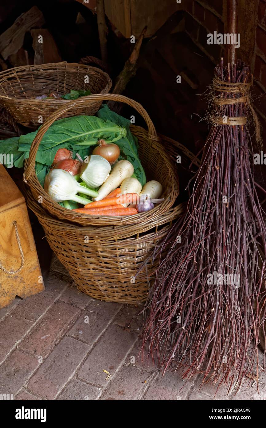 Scène rustique de panier de légumes mélangés, à côté d'un vieux balai méchant Banque D'Images