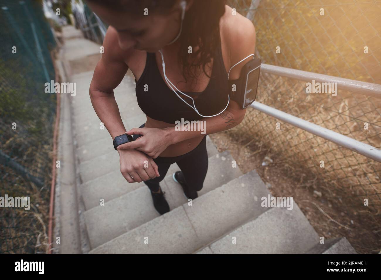 Sportswoman vérifiant l'heure sur une montre intelligente en se tenant sur un escalier. Une jeune femme sportive se prépare à courir le matin. Banque D'Images