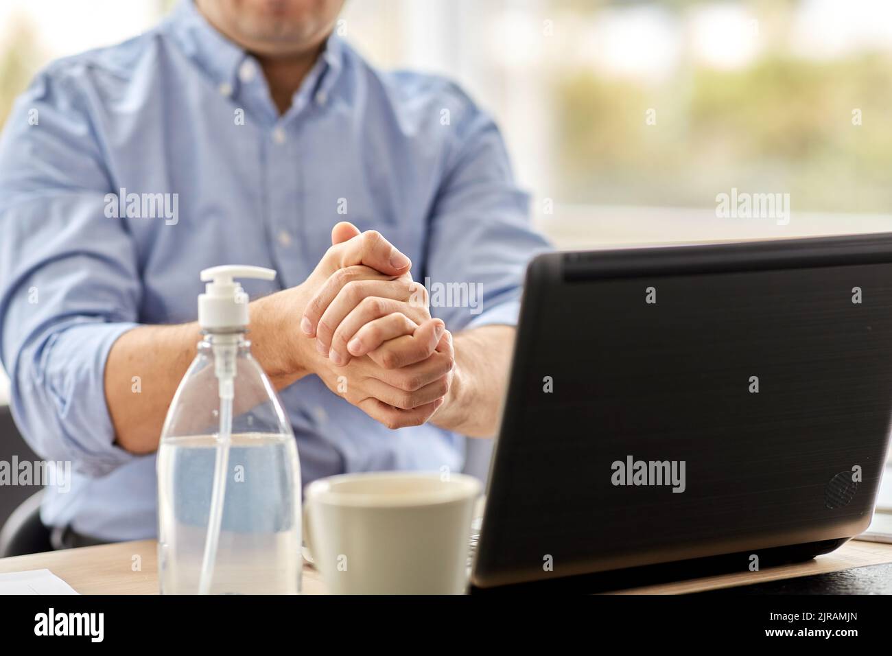 homme utilisant un désinfectant pour les mains au bureau à domicile Banque D'Images