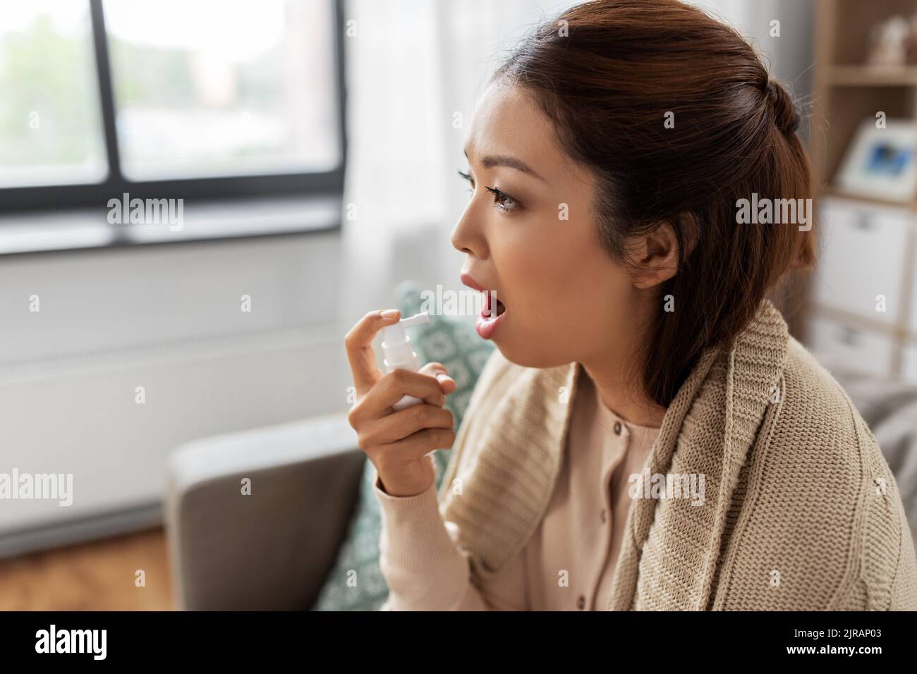 femme asiatique malade utilisant la médecine par pulvérisation orale à la maison Banque D'Images