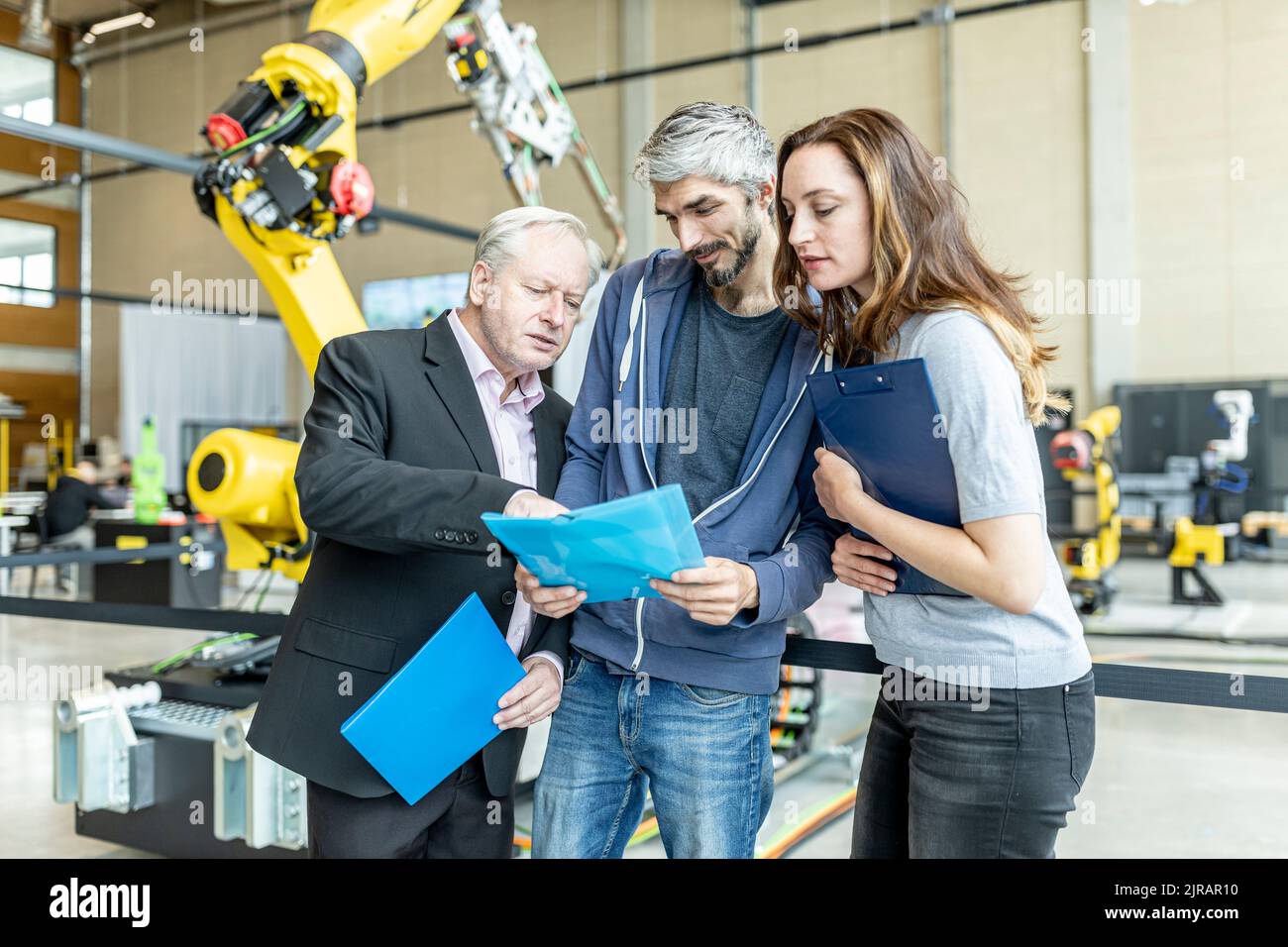 Responsable discutant du rapport technique avec des collègues devant le robot industriel Banque D'Images