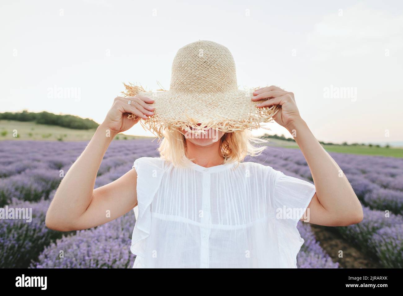 Femme couvrant le visage avec un chapeau dans le champ de lavande Banque D'Images