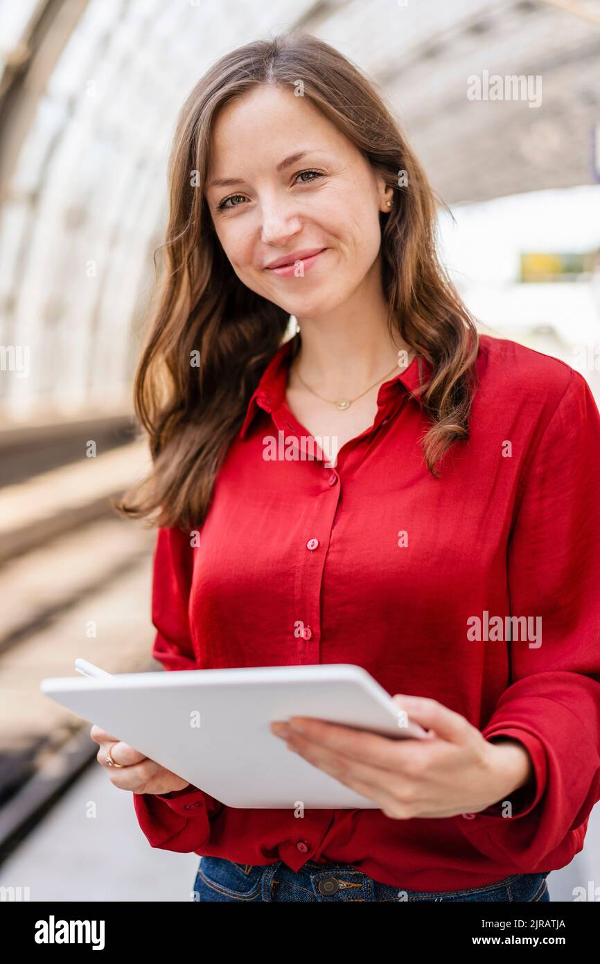 Femme souriante avec cheveux bruns tenant un Tablet PC Banque D'Images