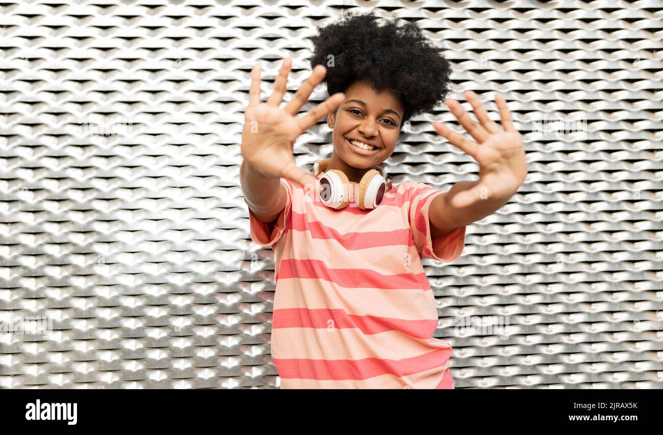 Femme souriante signe d'arrêt de gestuelle devant le mur Banque D'Images