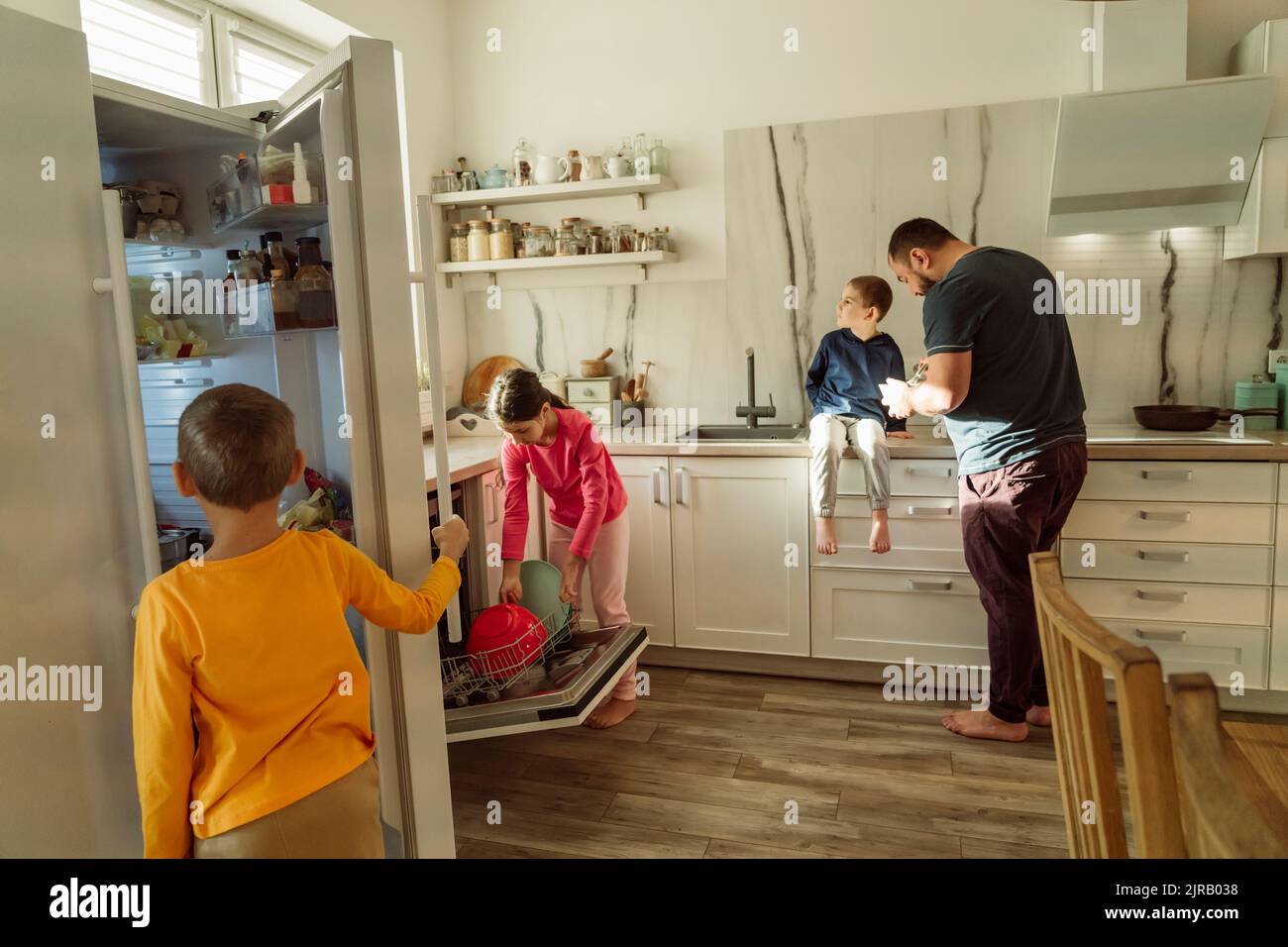 Homme avec enfants dans la cuisine à la maison Banque D'Images