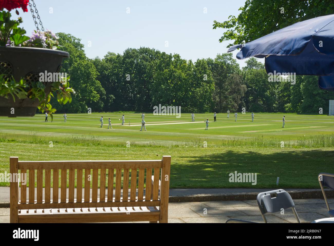 Joueurs sur le terrain pendant le match de cricket au château d'Arundel, dans l'ouest du Sussex, en Angleterre. Avec patio et banc en premier plan. Banque D'Images
