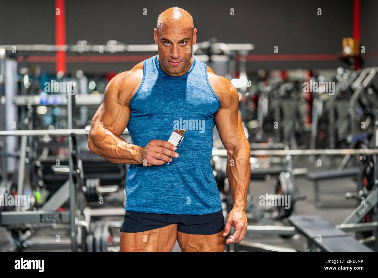 Bodybuilder musculaire tenant la barre de protéines dans la salle de gym Banque D'Images