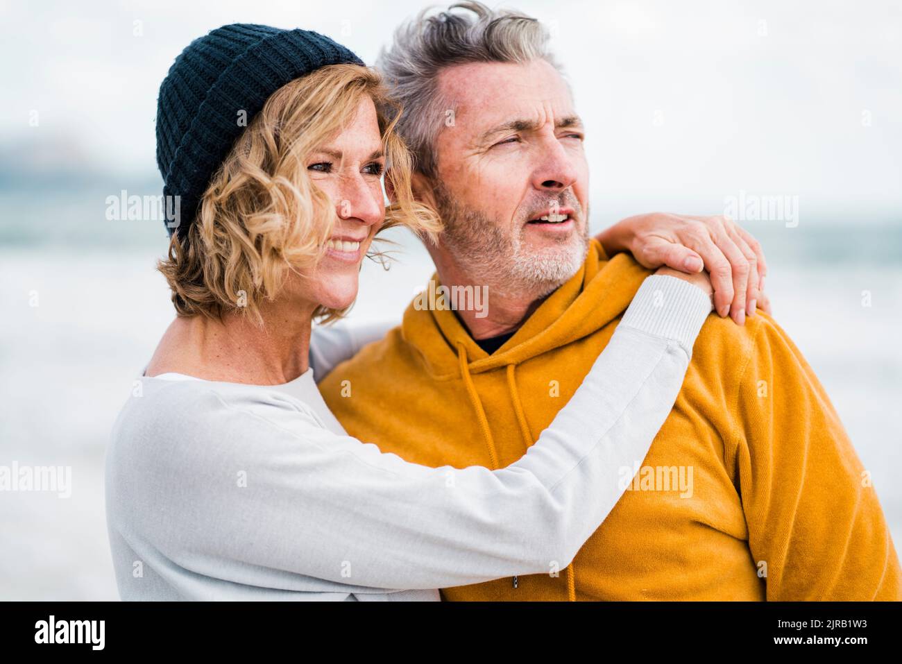 Femme heureuse avec le bras autour de l'homme à la plage Banque D'Images