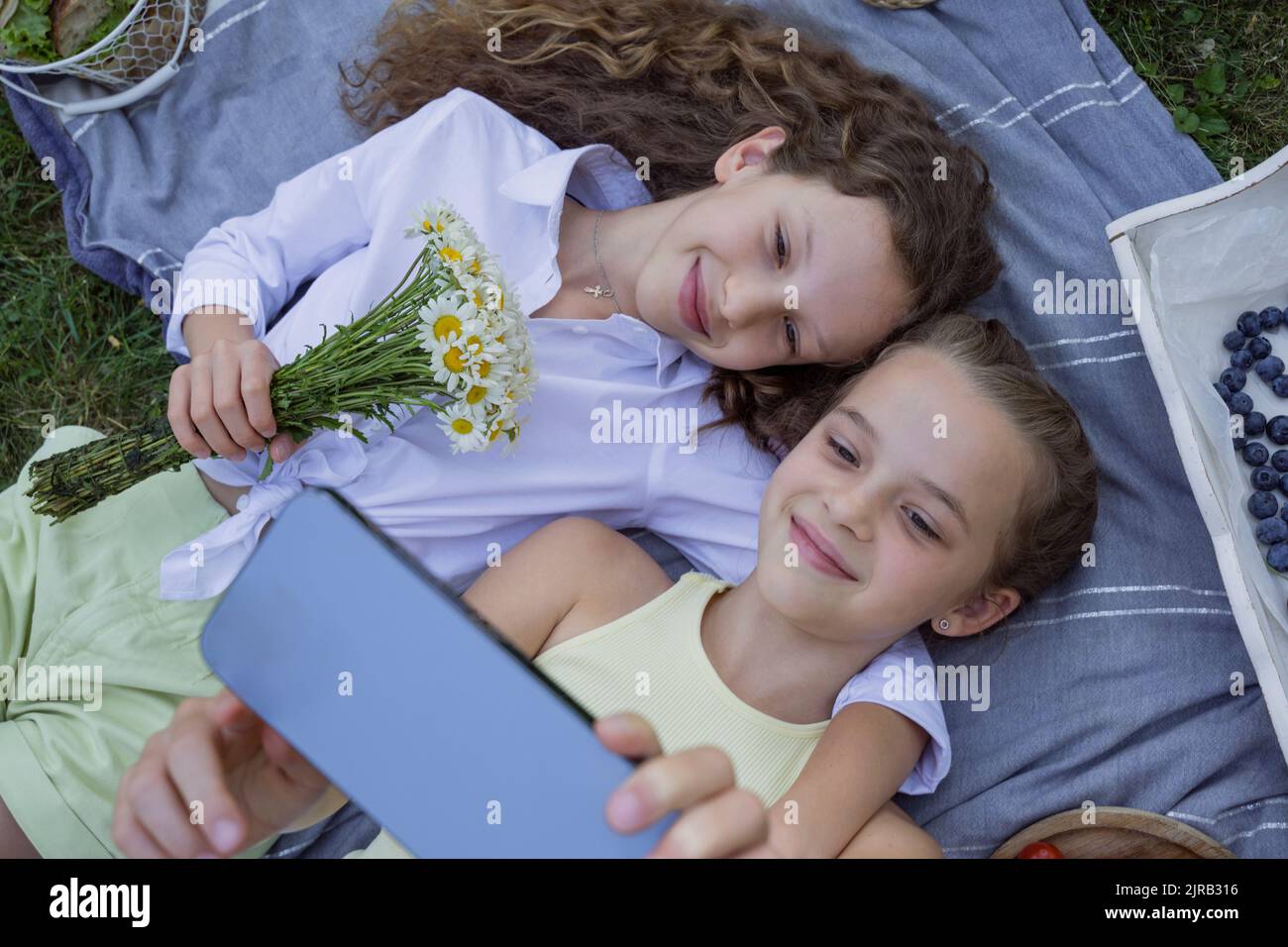 Des filles souriantes emmenaient le selfie sur un smartphone allongé dans un parc Banque D'Images