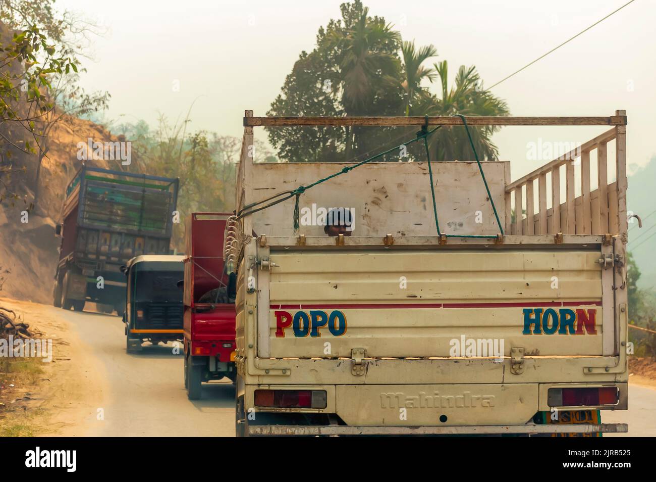 Un ouvrier / ouvrier de salaire quotidien assis sur la caisse d'un pick-up Mahindra, tout en voyageant entre les villes indiennes. Banque D'Images