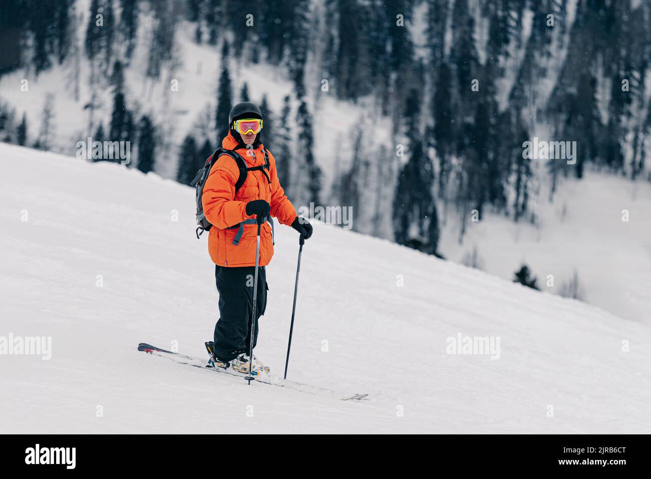Skieur portant un casque et des lunettes debout sur la neige Banque D'Images