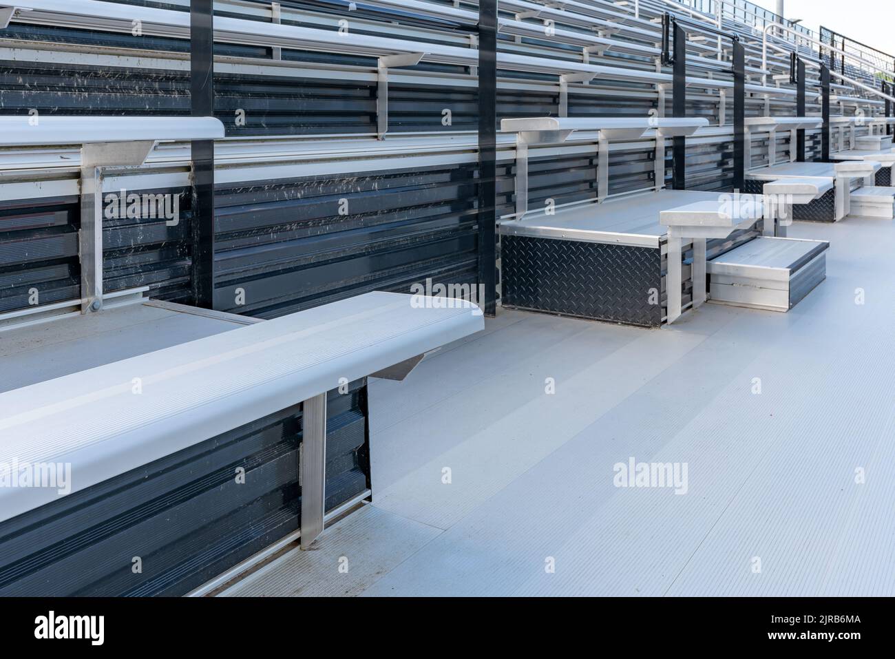 Sièges de gradins accessibles depuis le stade en métal vide avec sièges d'accompagnement dans l'allée avant. Banque D'Images