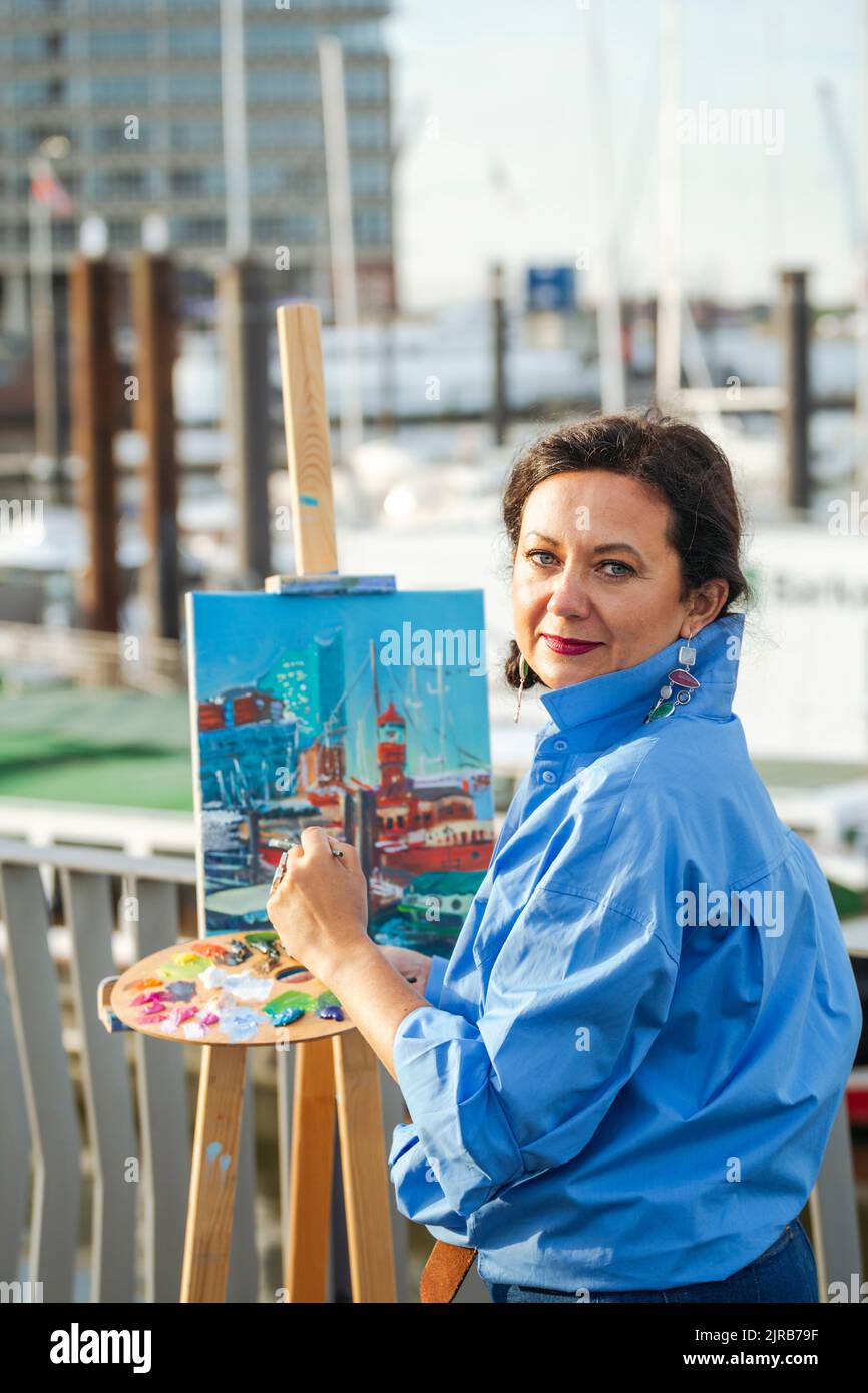 Artiste souriant avec peinture de palette au port Banque D'Images