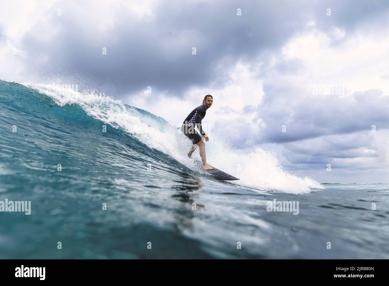 Homme surfant sur les vagues qui éclabousse en mer Banque D'Images