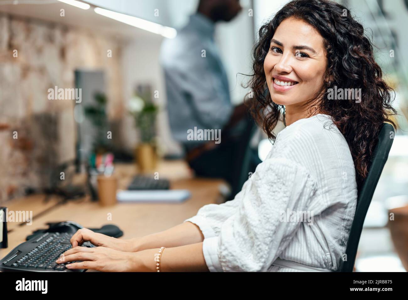 Femme d'affaires souriante travaillant sur un ordinateur au bureau Banque D'Images