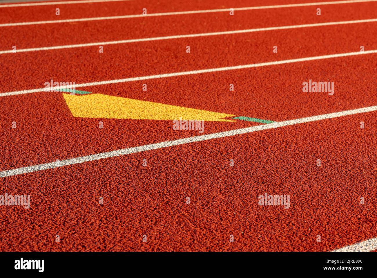 Gros plan du début d'une zone d'échange sur une nouvelle piste de course rouge avec lignes de voies blanches et autres marquages. Banque D'Images