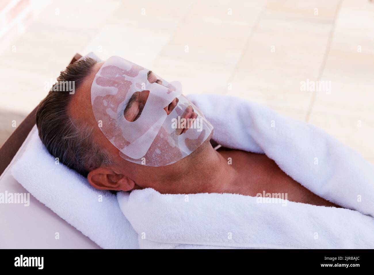 Homme mature avec masque facial relaxant au spa de la piscine Banque D'Images
