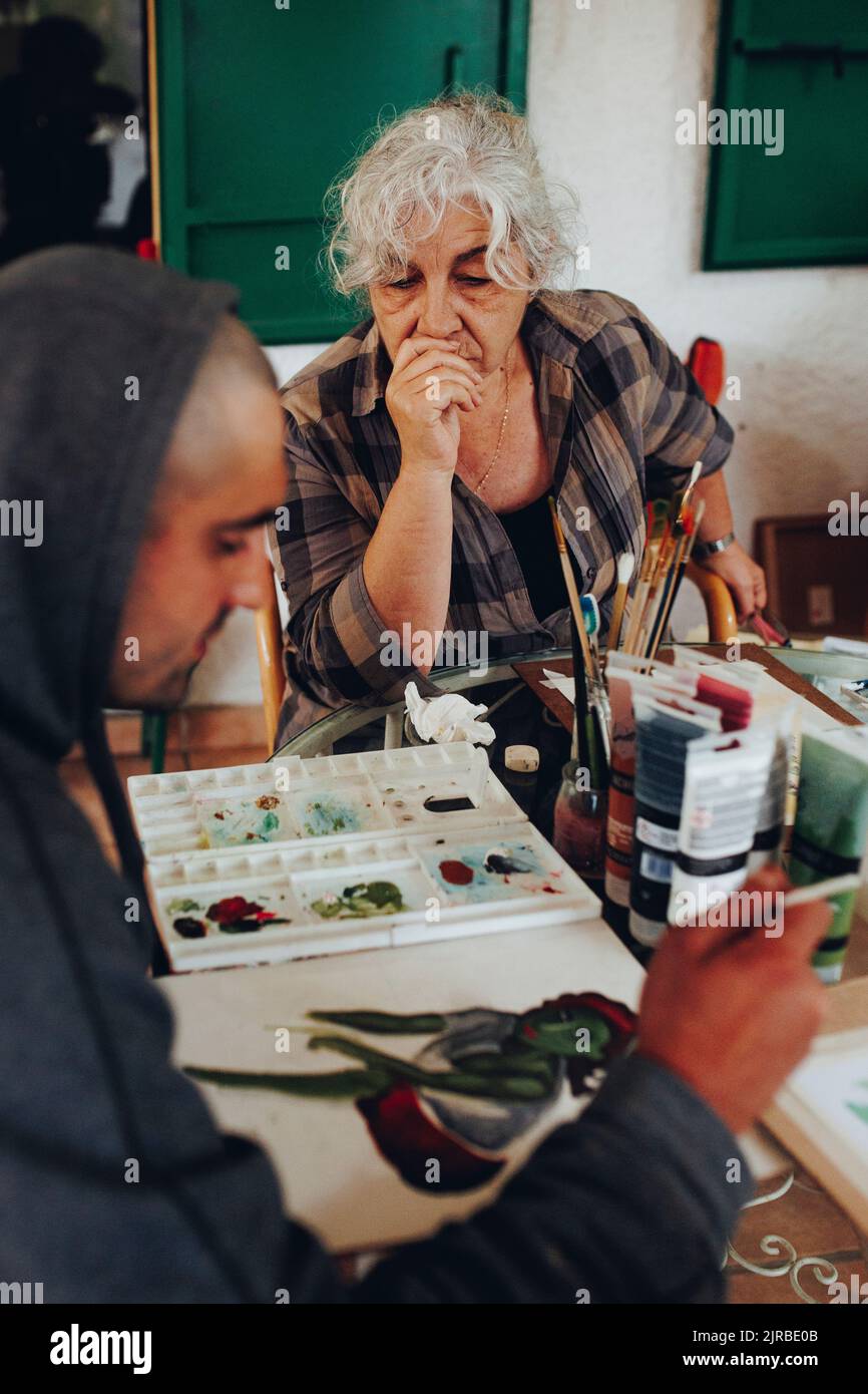 Femme âgée regardant la peinture d'artiste sur papier Banque D'Images