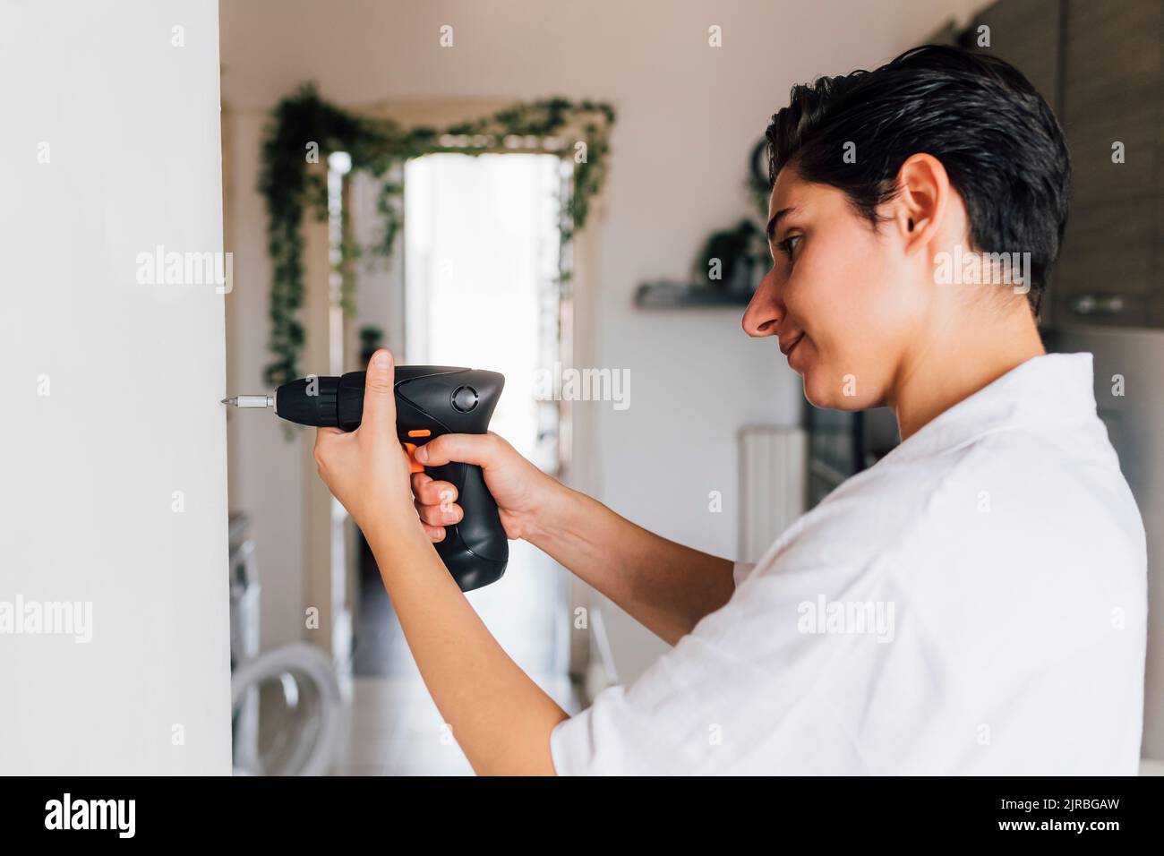 Jeune artisan utilisant le foret à la maison Banque D'Images