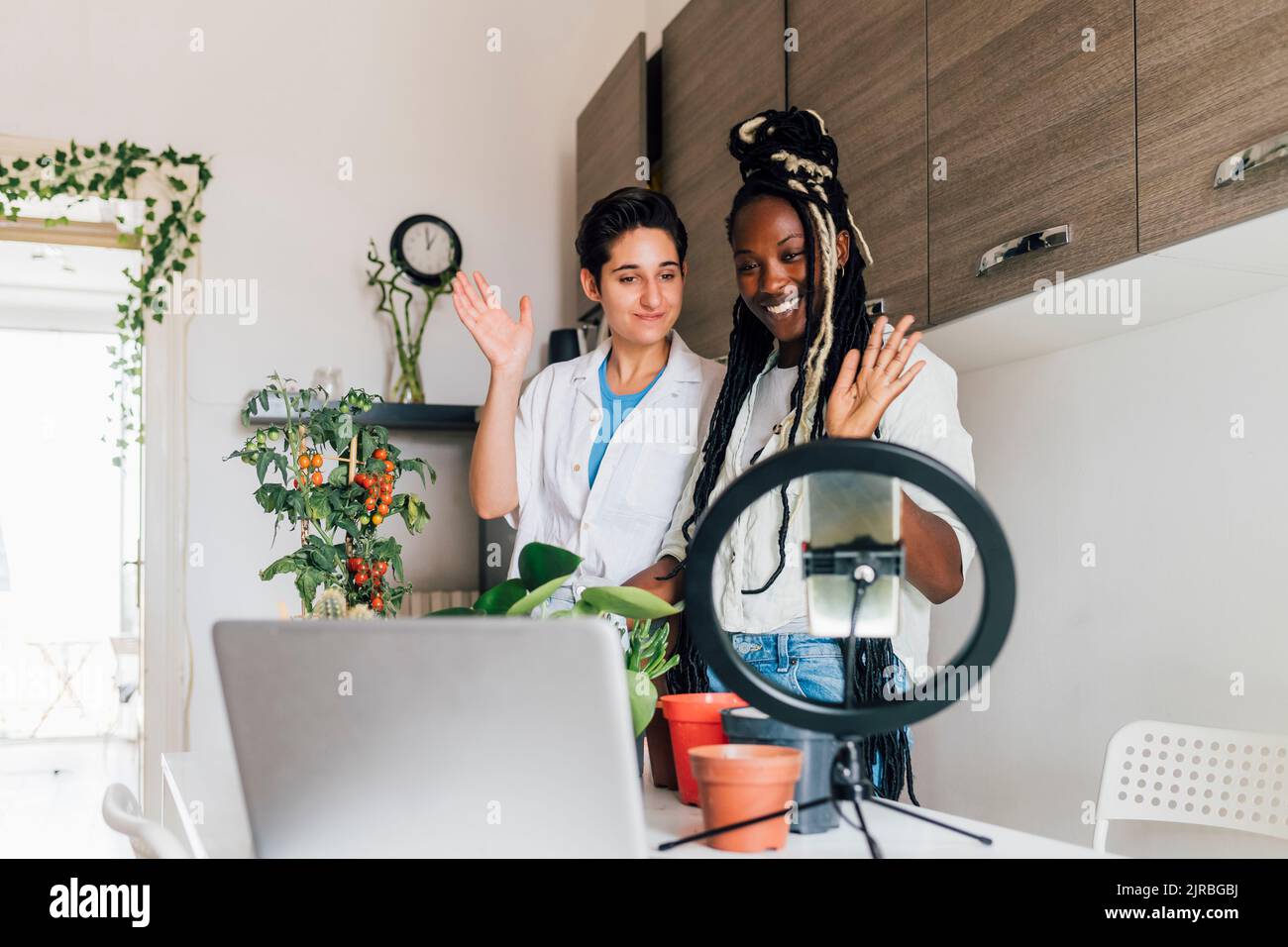 Femme souriante avec une amie filmant des conseils de soin d'usine à la maison Banque D'Images