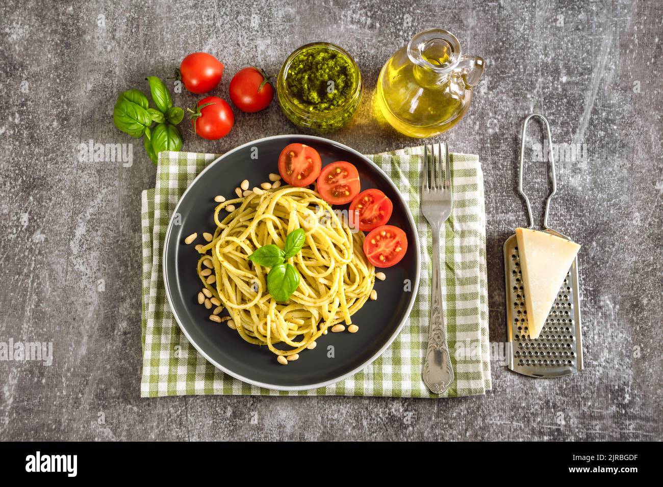 Pesto de pâtes avec fourchette et sauce pesto fraîche sur fond de béton gris. Spaghetti italiens traditionnels et ingrédients alimentaires sauce pesto, tomate, parme Banque D'Images