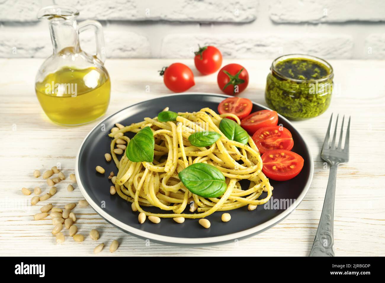 Pesto aux pâtes avec fourchette et sauce pesto fraîche sur fond de bois blanc. Spaghetti italiens traditionnels et ingrédients alimentaires sauce pesto, tomate, parmes Banque D'Images