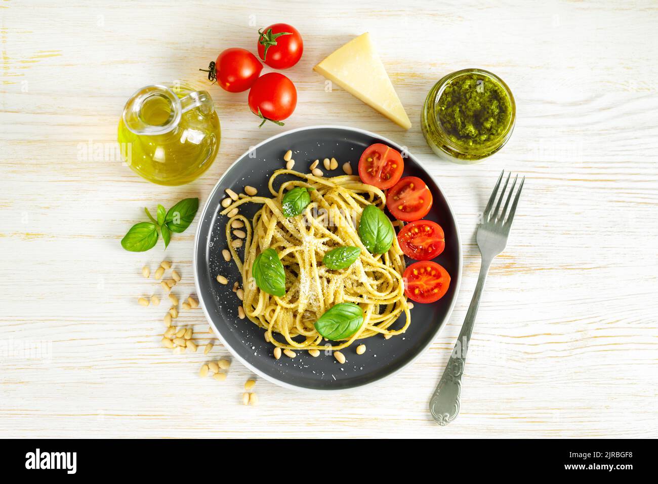 Pesto aux pâtes avec fourchette et sauce pesto fraîche sur fond de bois blanc. Spaghetti italiens traditionnels et ingrédients alimentaires sauce pesto, tomate, parmes Banque D'Images