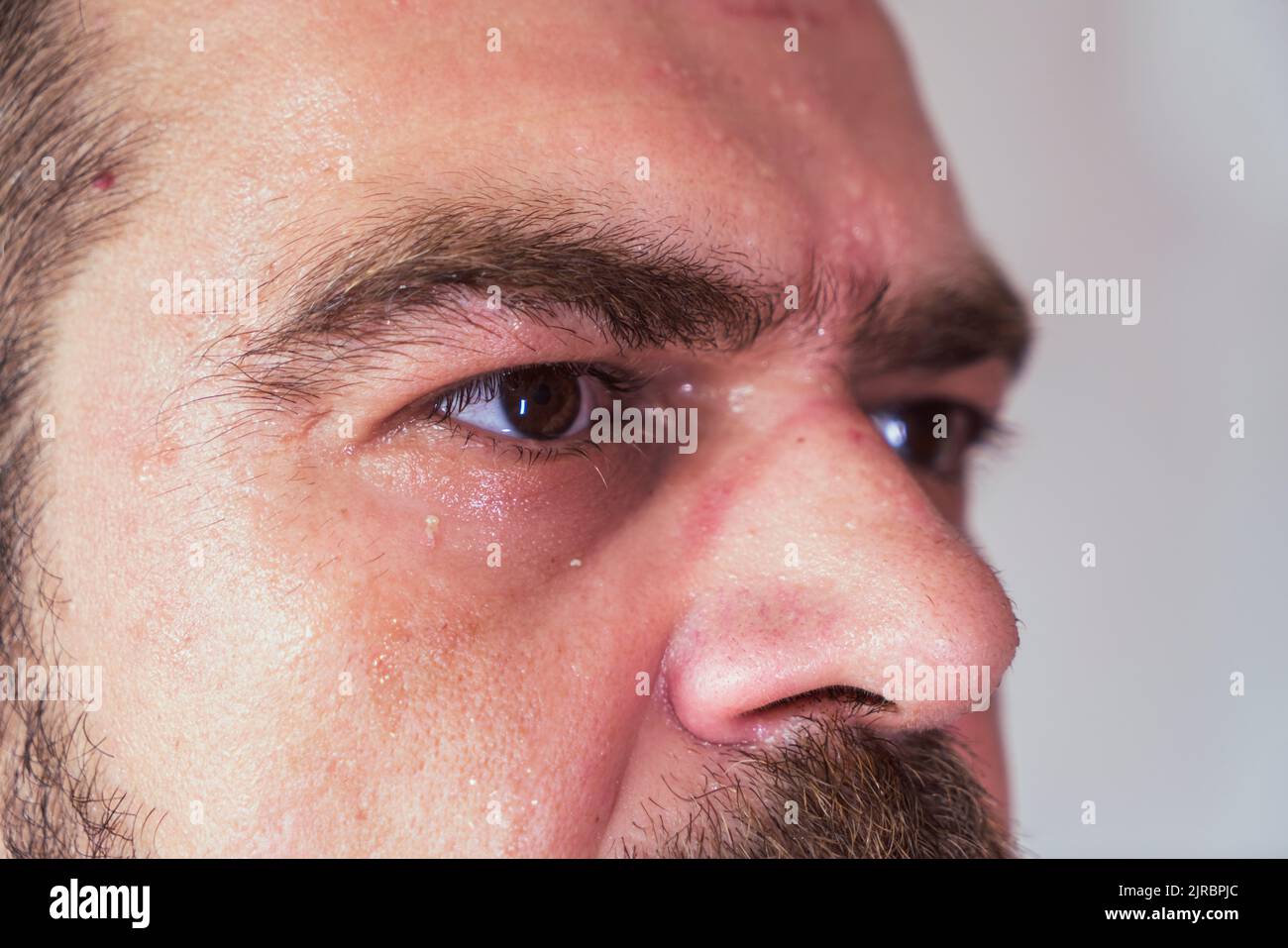 Sueur, barbu, beau homme caucasien regardant vers l'avant sérieusement avec une mise au point sélective, un gros plan extrême. Banque D'Images