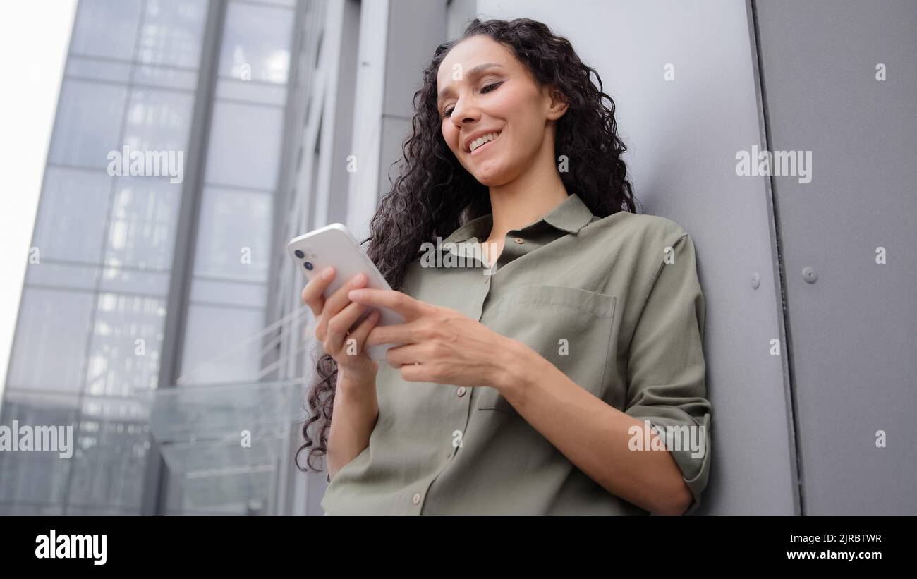 Confiant 30s femme adulte succès femme d'affaires souriant SMS dans l'application mobile en utilisant le téléphone en ligne service d'e-commerce dans le chat avec Internet Banque D'Images
