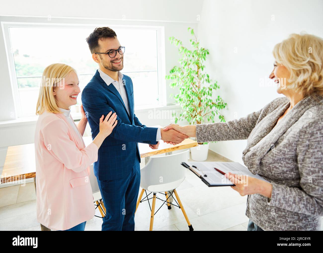 un jeune couple qui tremble les mains traite contrat d'investissement immobilier agent d'accord d'affaires poignée de main signature Banque D'Images