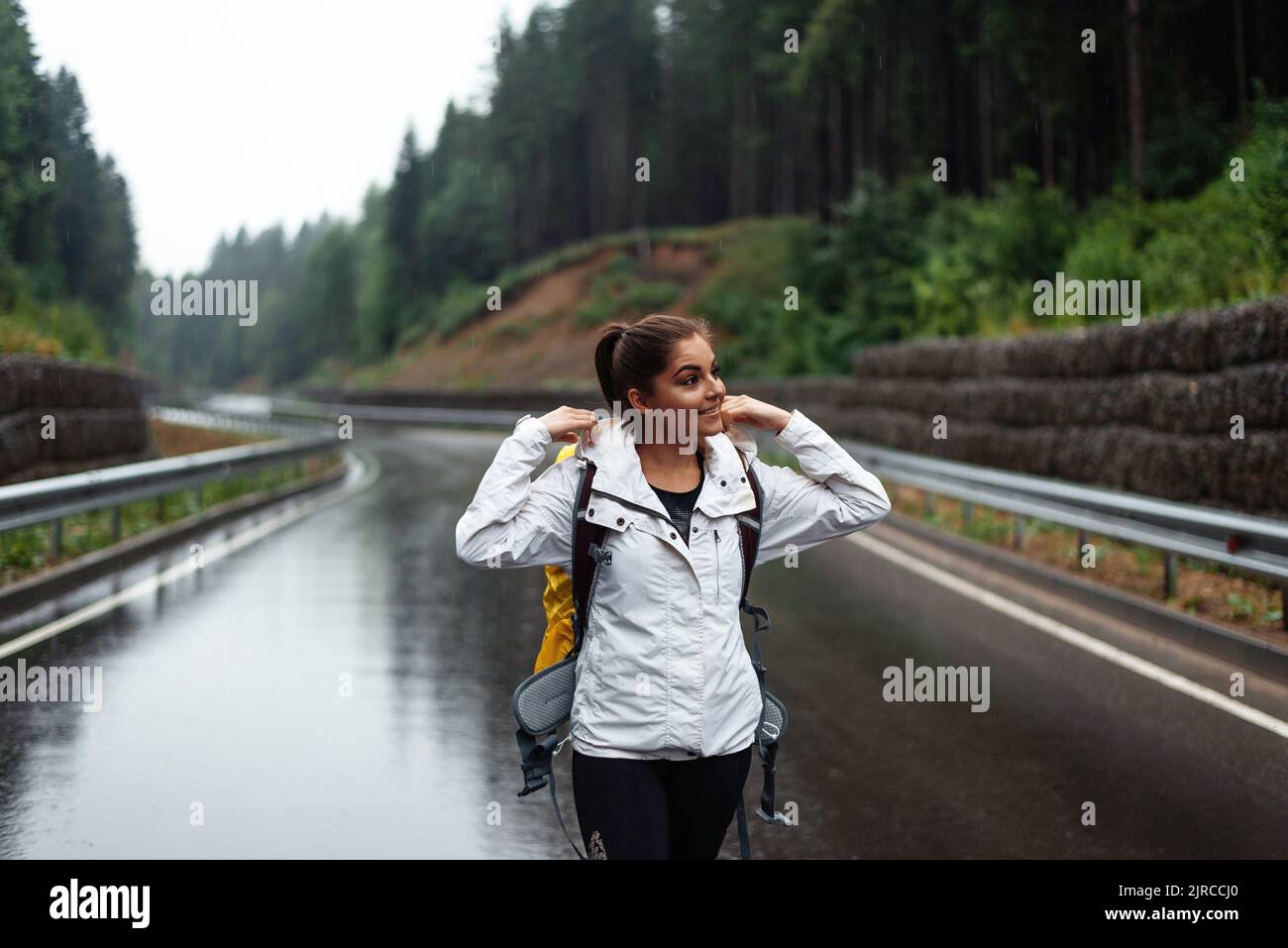 Randonneur jeune femme regardant loin en marchant avec sac à dos jaune dans la nature dehors. Happy girl est trekking sur la route de la forêt avec sac à dos de camping. Par Banque D'Images