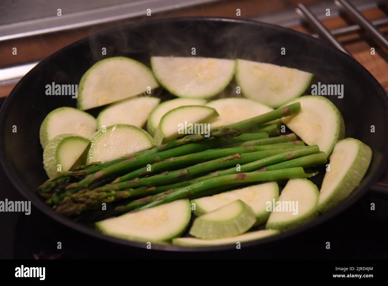 Un gros plan d'asperges et de courgettes dans une poêle noire Banque D'Images