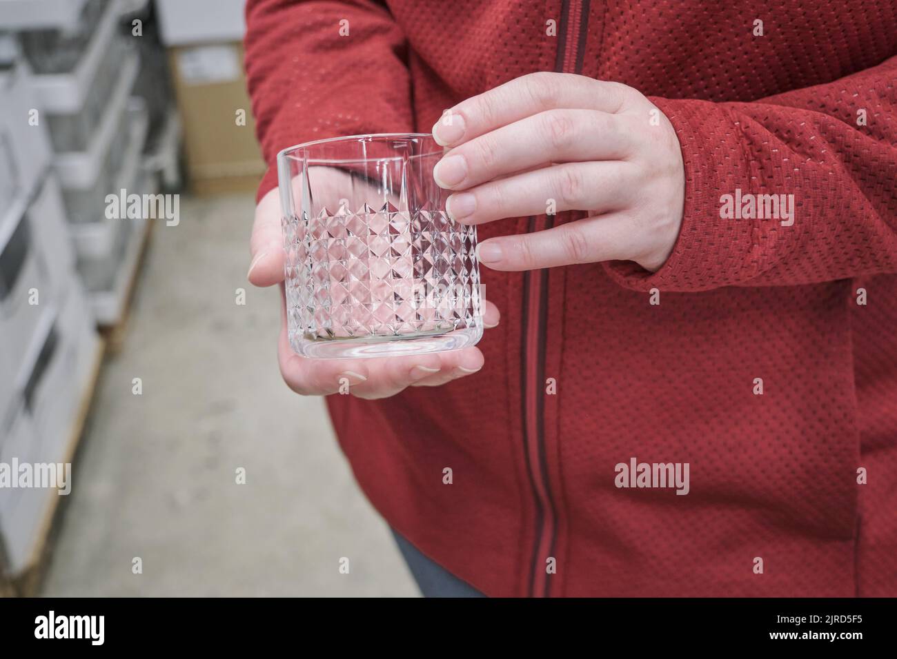 Une fille caucasienne achète un verre transparent pour les boissons alcoolisées fortes en magasin Banque D'Images
