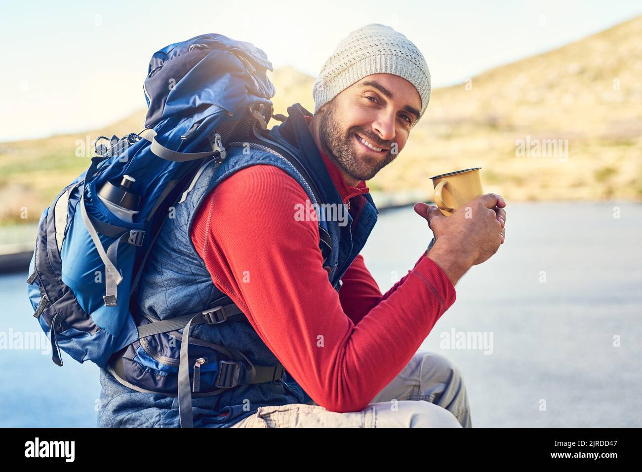 On ne peut pas trouver mieux que le café et la vue. Portrait d'un randonneur heureux buvant un café tout en admirant une vue sur le lac sur un sentier. Banque D'Images