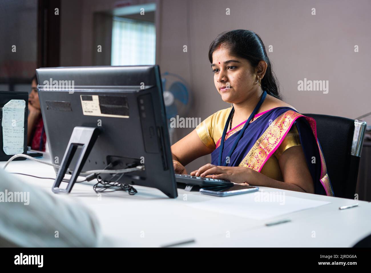 Employé de banque sérieux occupé à travailler sur l'ordinateur devant le client - concept de l'autonomisation des femmes, le travail ou la carrière et le service bancaire. Banque D'Images