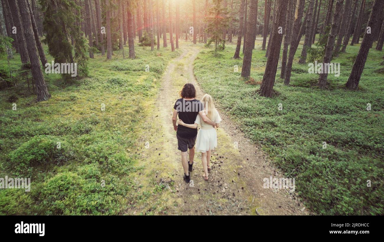 Jeune, charmant couple amoureux marchant dans un bras de forêt luxuriant et mossy dans le bras au coucher du soleil dans la soirée Banque D'Images