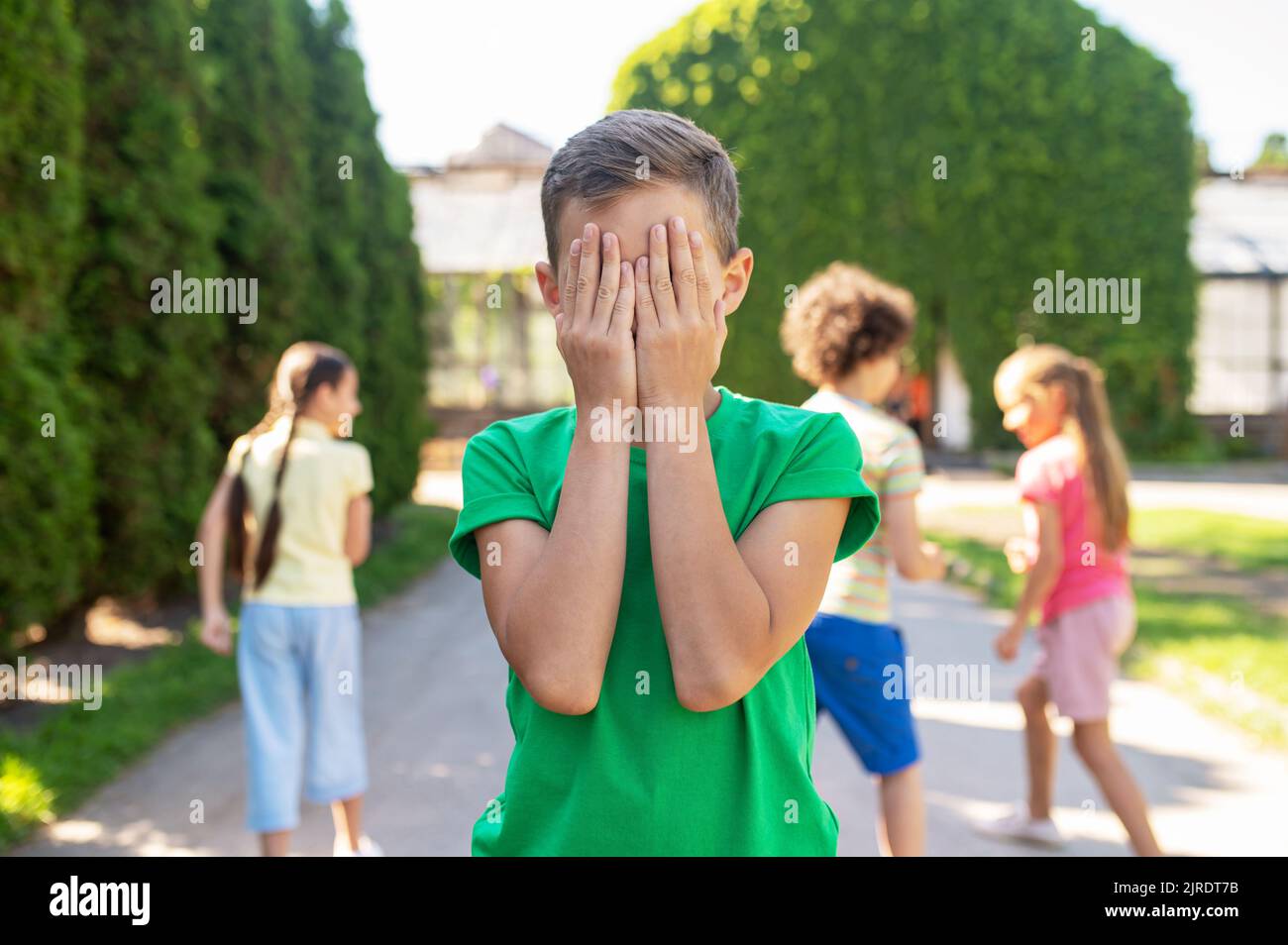 Garçon couvrant les yeux avec les mains et cachant des enfants Banque D'Images