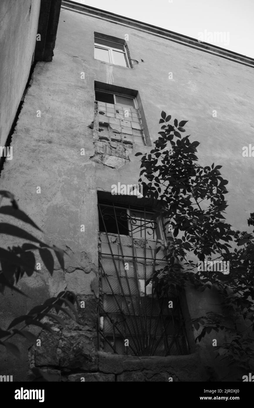 Image verticale en niveaux de gris d'un ancien bâtiment abandonné avec des fenêtres cassées Banque D'Images