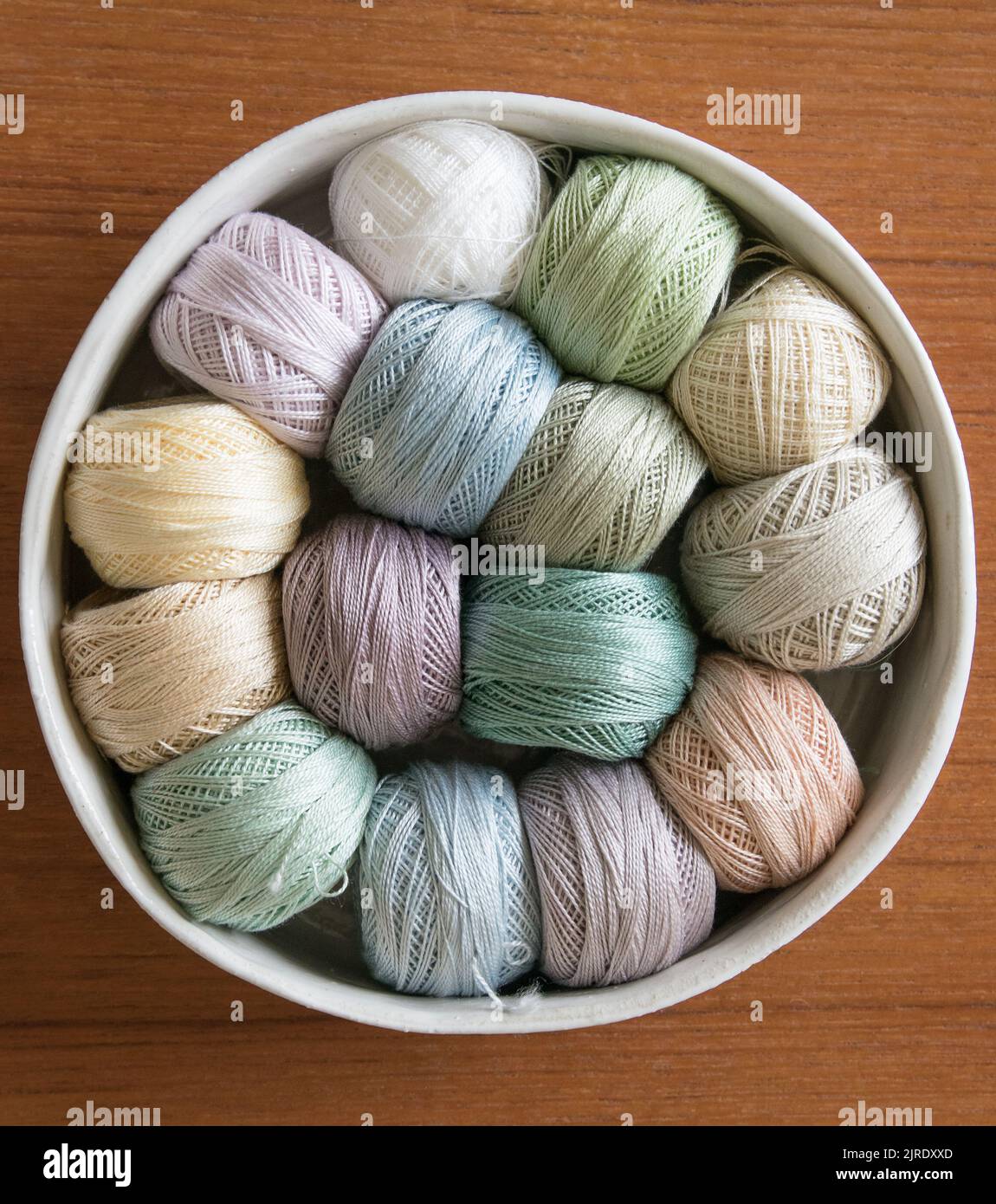 Tons doux couleurs broderie rouleaux de fil dans un bol en argile fait à la main. Banque D'Images