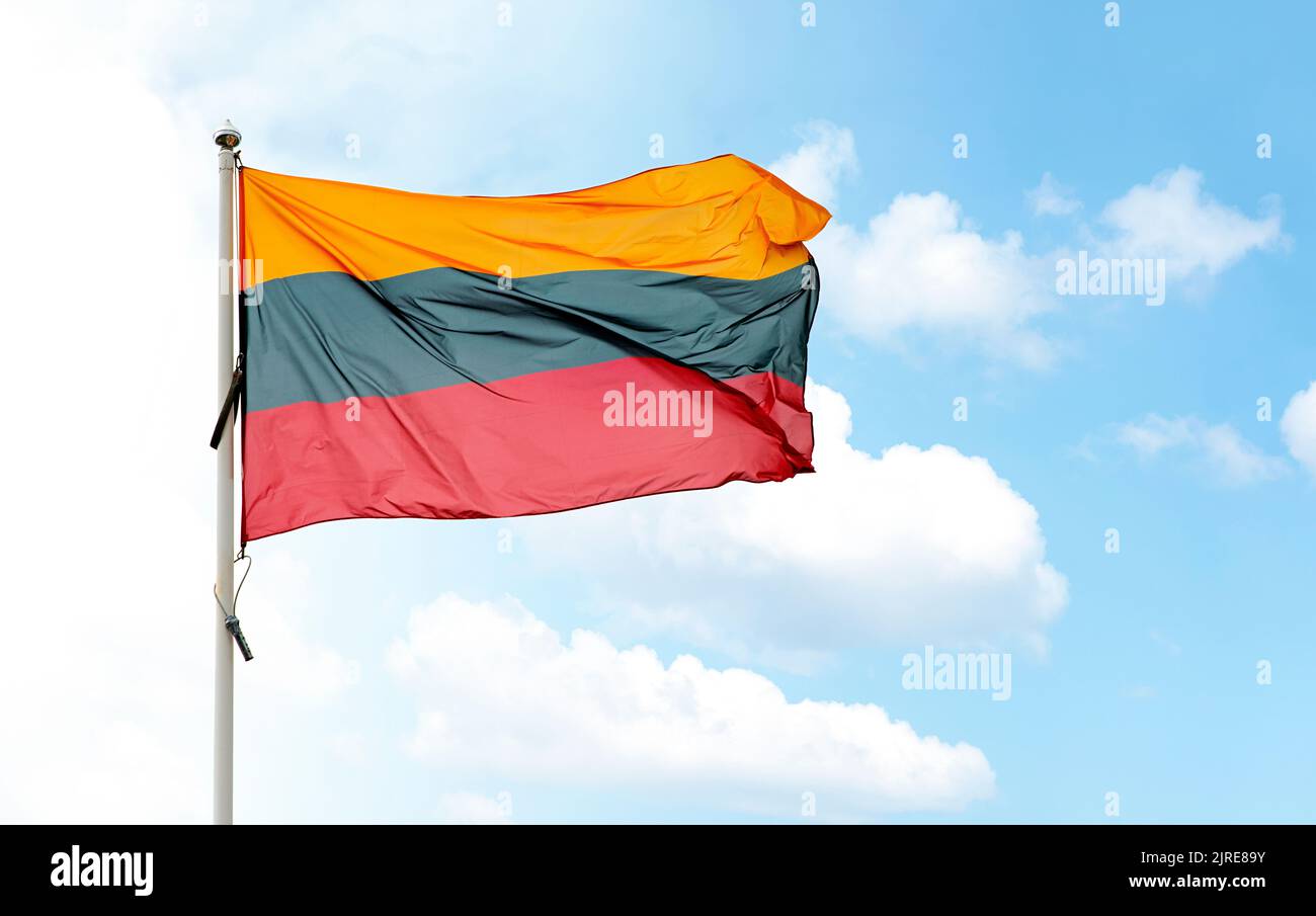 Grand drapeau national lituanien sur le mât agitant dans le vent contre le ciel bleu nuageux Banque D'Images