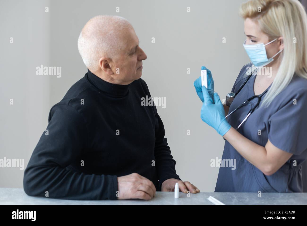 Infirmière effectuant un test pcr du coronavirus sur un homme âgé à la maison Banque D'Images