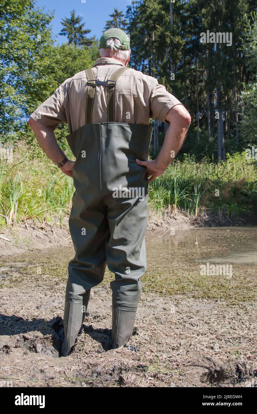 Là où l'eau est normalement d'un mètre et cinquante de profondeur, le pêcheur se tient maintenant seulement à la cheville-profondeur dans la boue. Banque D'Images