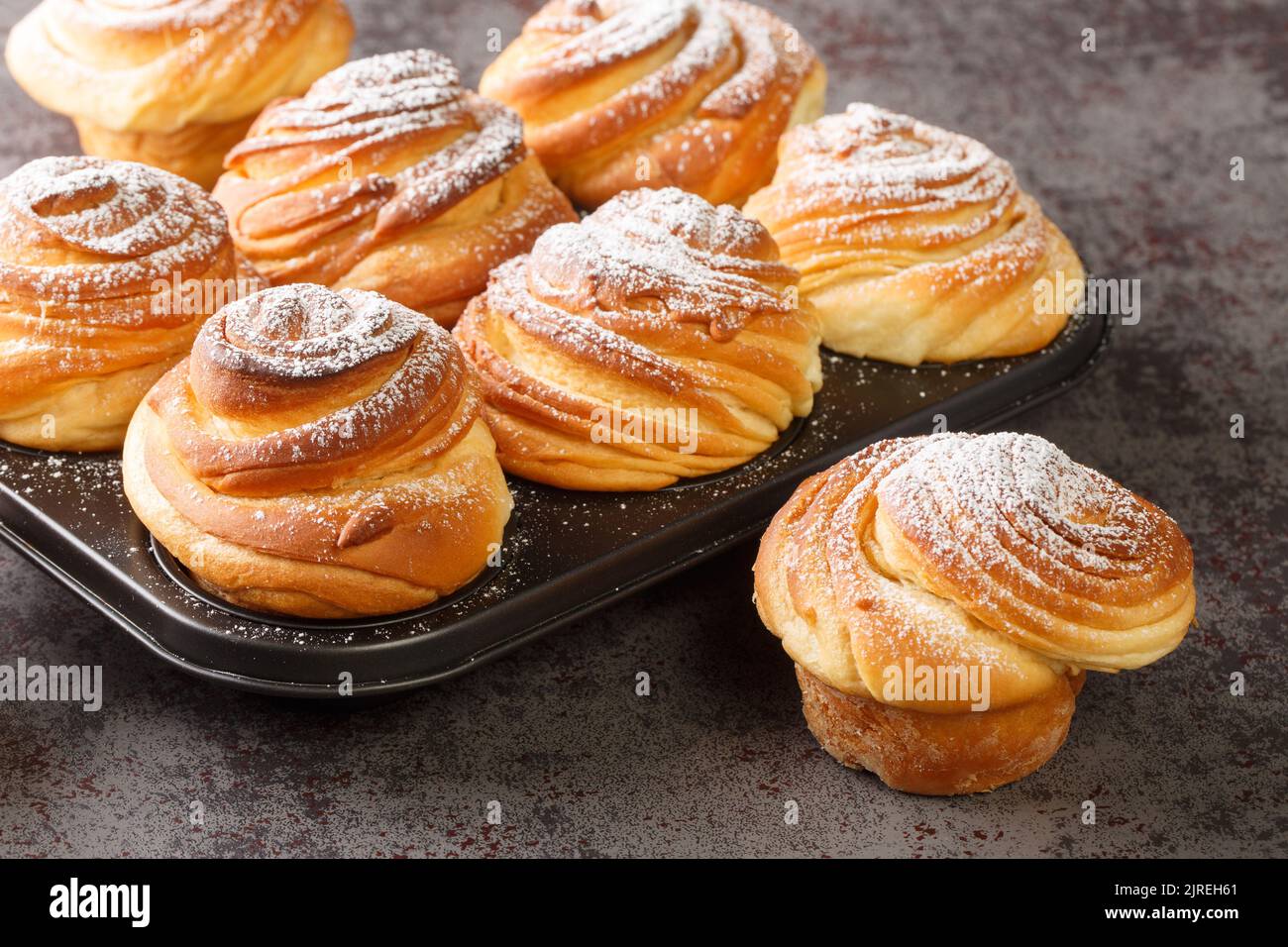 Pâtisseries maison, cruffins, muffin à la poudre de sucre, sur fond sombre, focase sélective gros plan. Horizontale Banque D'Images
