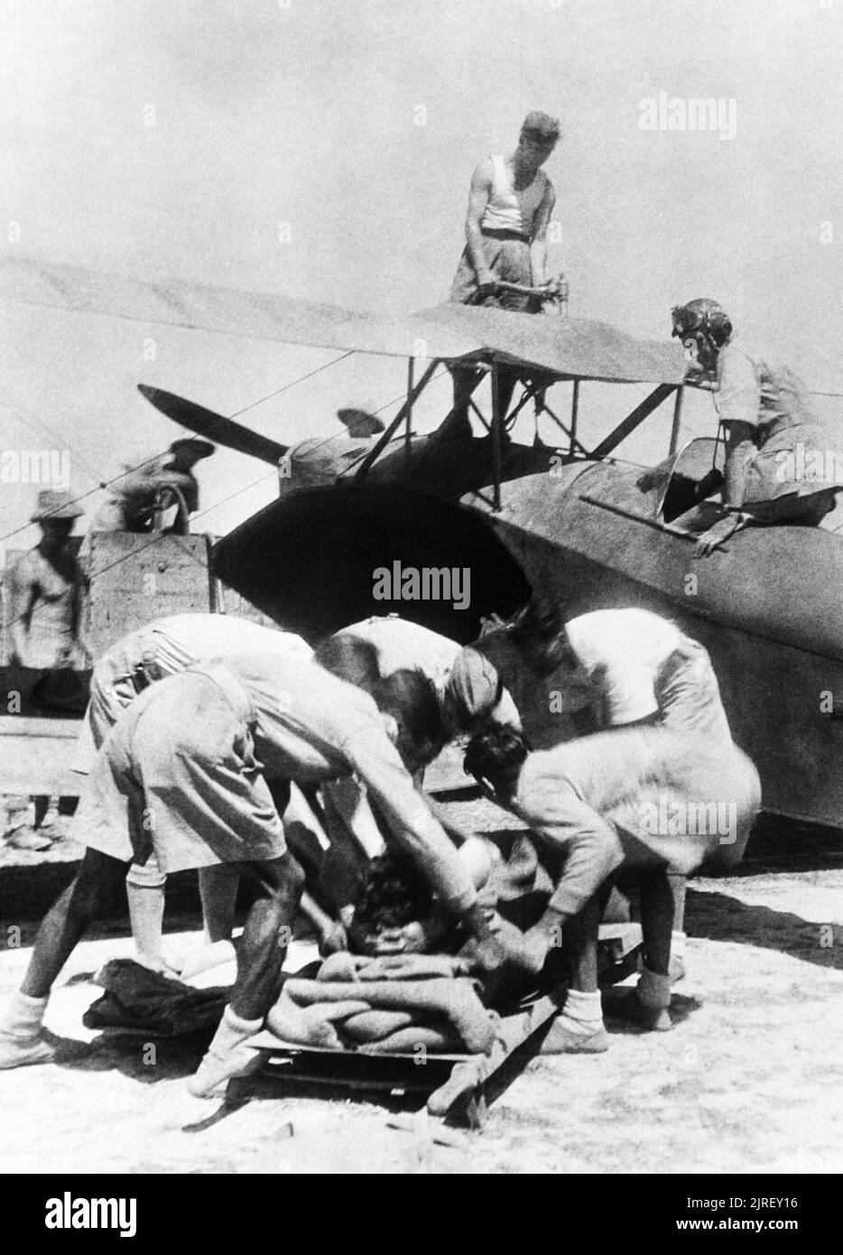 Opérations de la Royal Air Force dans l'Extrême-Orient, 1941-1945. Un soldat blessé, évacué par avion depuis les combats dans la vallée du Kalapanzin, est abaissé sur une civière par les préposés aux soins à un stade avancé de l'aérodrome de l'Arakan, comme l'ambulance, un avion de Havilland DH.83 Fox Moth, est approvisionné. Le pilote, un ancien policier de Londres , le Lieutenant d'Edwin E Mackay de Carlisle, montres à partir de son poste de pilotage. Banque D'Images